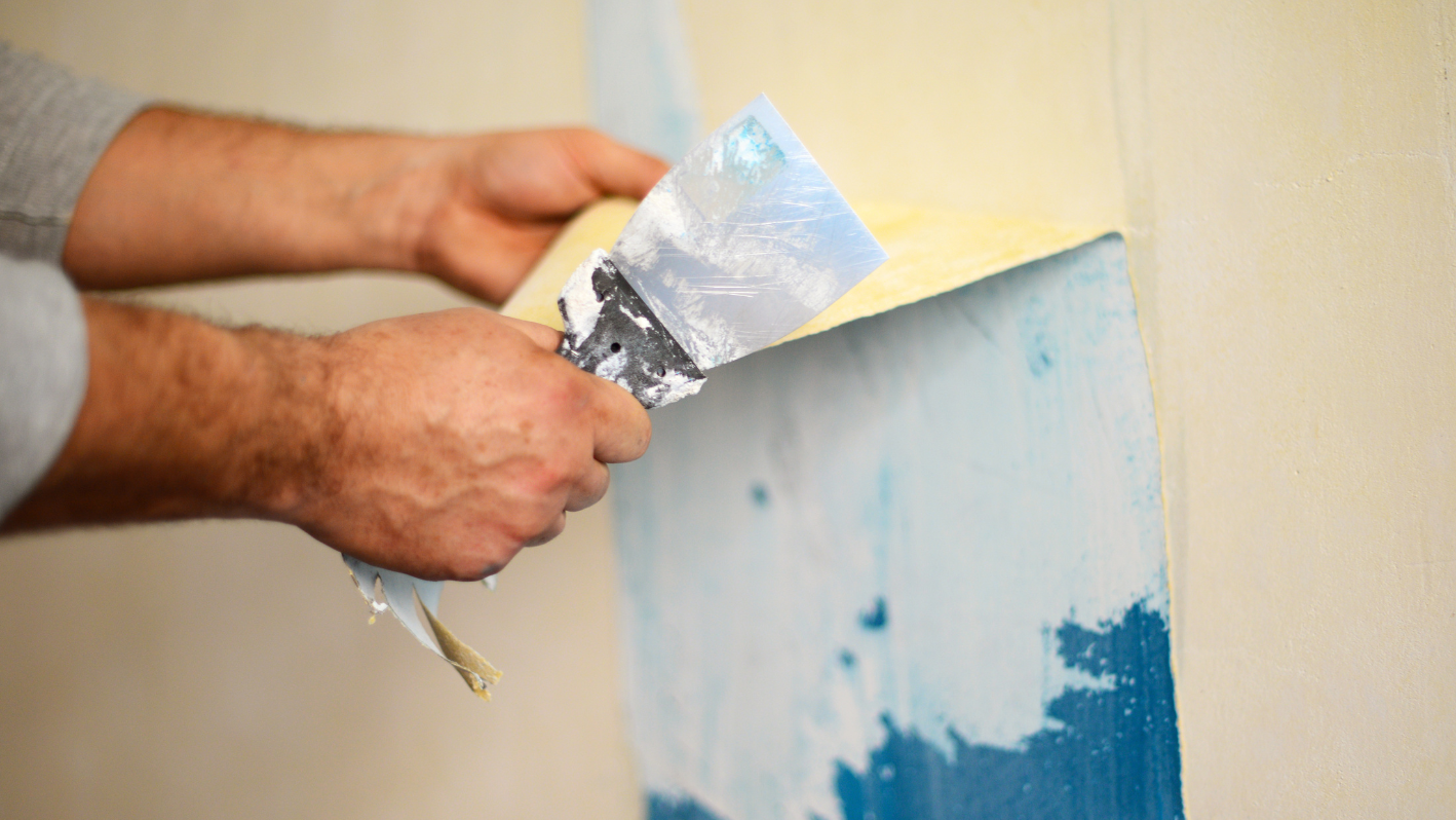 A person painting a wall with blue and yellow paint